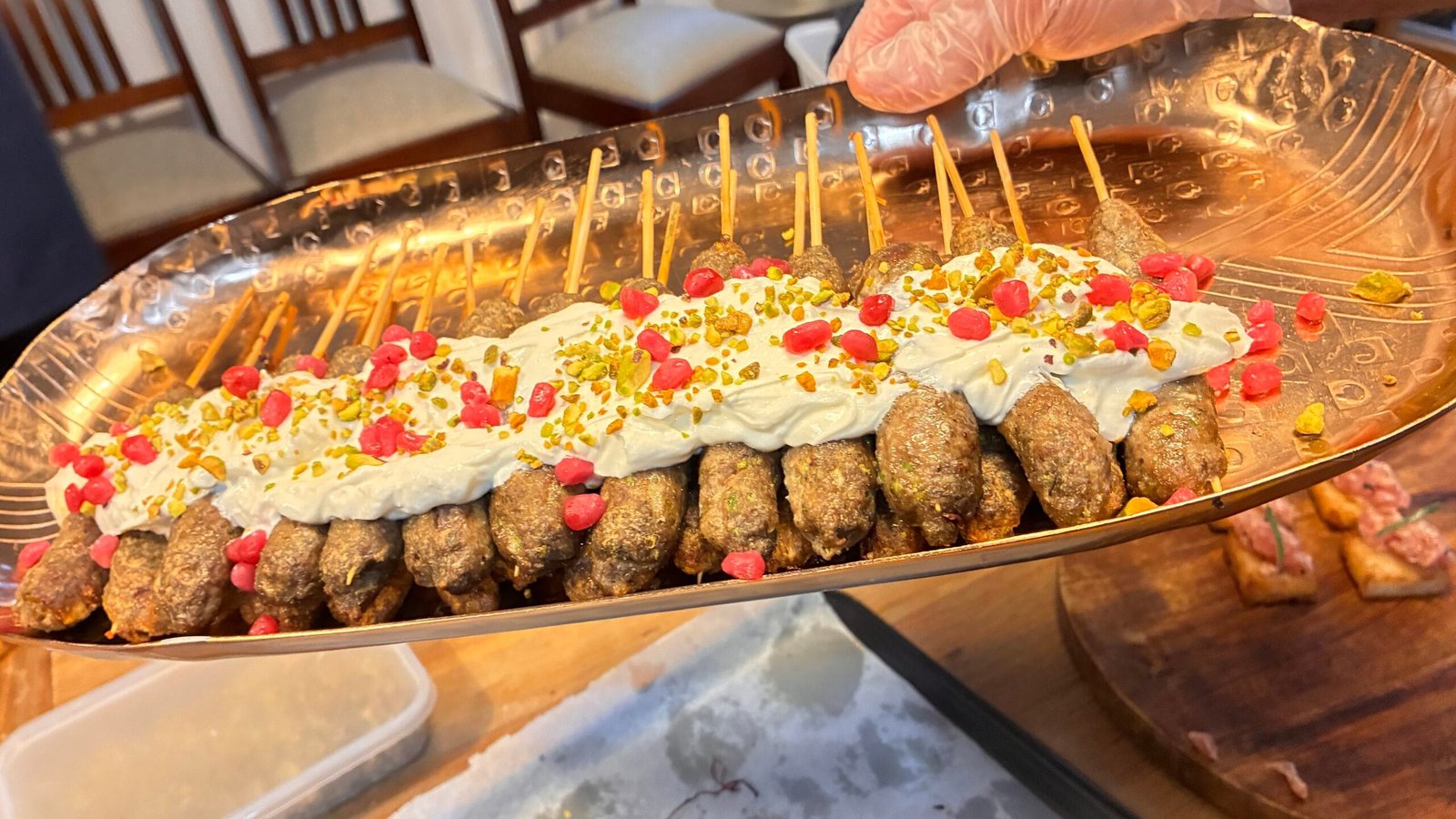 Lamb koftas by HLB catering, in skewers, topped with lemon yogurt labneh, pistachio crumbs and pomegranate seeds